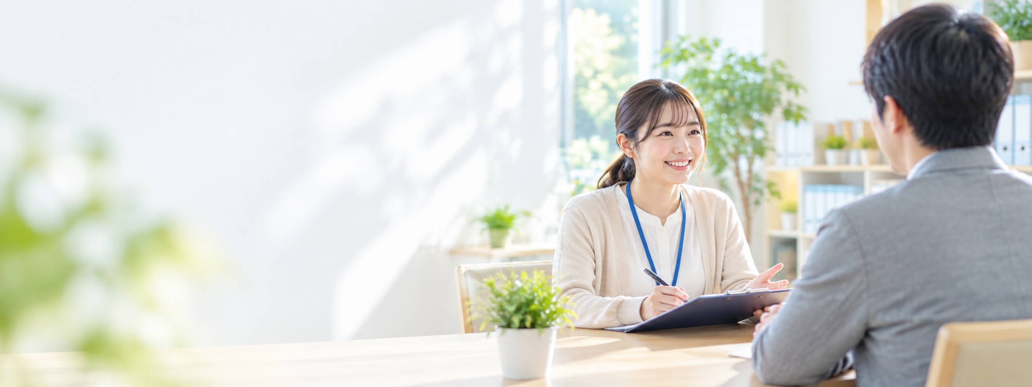 事業所の相談の場面で、職員が相談に来た方の話を聞きながら記録している様子