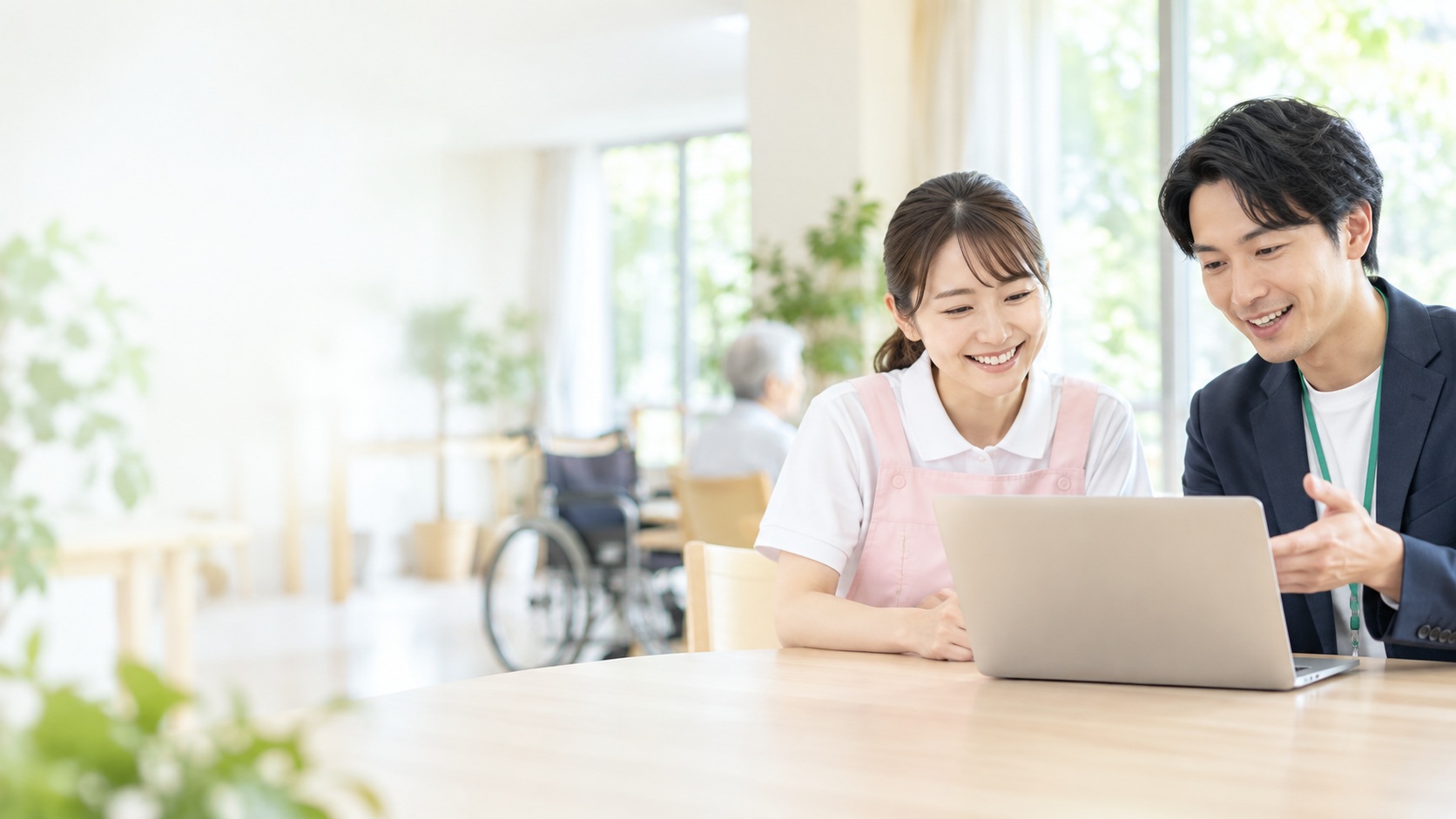 福祉施設で、介護スタッフとIT支援者がノートパソコンの画面を一緒に見ながら話している様子